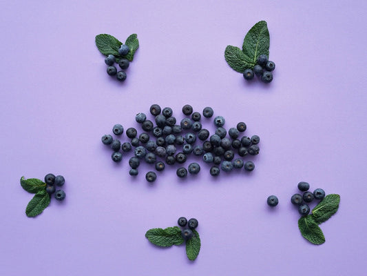 Mirtilli e foglie di menta sono disposti su una superficie viola.