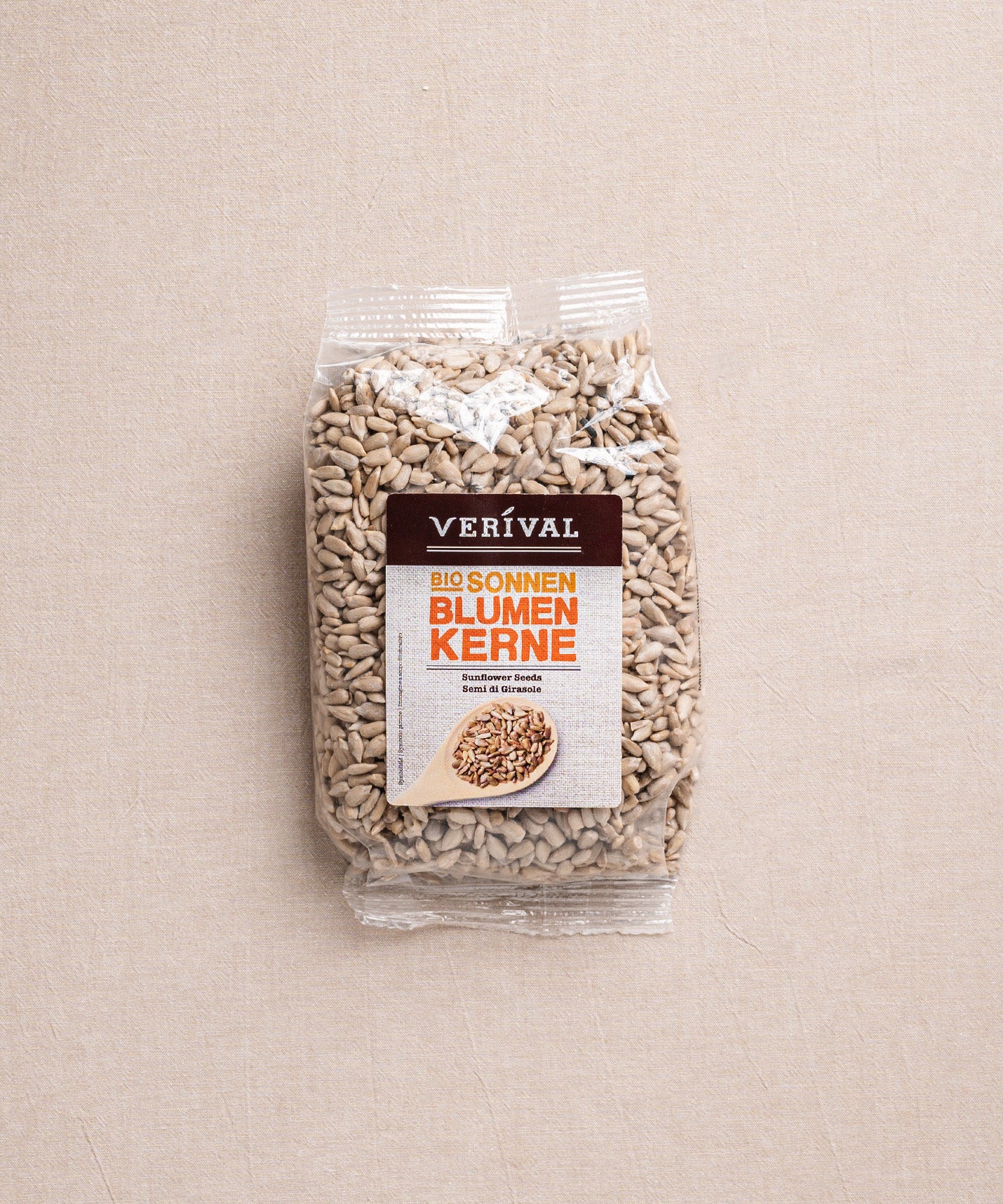 Eine Packung Sonnenblumenkerne von Verival Bio liegt auf einem beigen Untergrund. Der durchsichtige Folienbeutel enthält 100 % antioxidantienreicher Bio-Sonnenblumenkerne. Auf dem Etikett ist ein Holzlöffel voller Sonnenblumenkerne abgebildet.