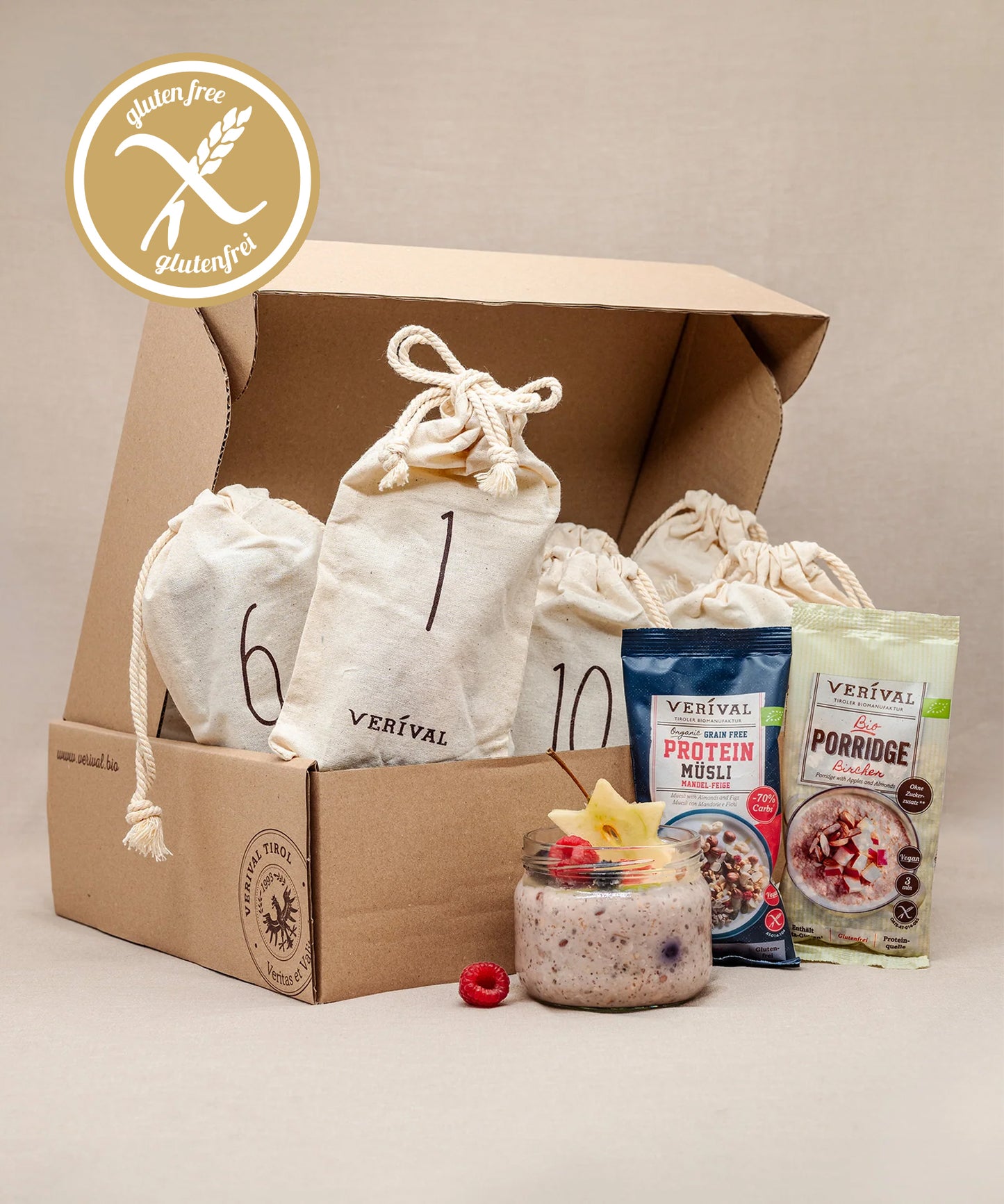 Das Verival Bio GmbH Adventskalender-Säckchen Glutenfrei besteht aus einer Pappschachtel, sechs Kordelzugbeuteln, zwei Packungen Verival Vollkornmüsli, einer Müsli- und einer Obstschale sowie einem glutenfreien Etikett in der linken oberen Ecke.