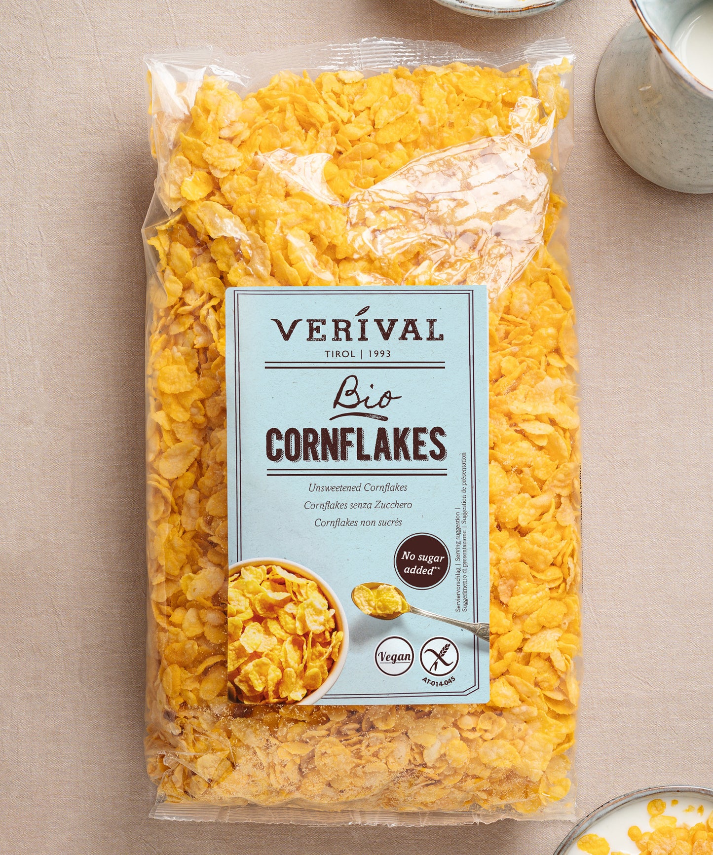 Eine durchsichtige Tüte Bio-Cornflakes ungesüßt der Verival Bio GmbH mit einem blauen Etikett, auf dem die Zertifizierungen glutenfrei, ohne Zuckerzusatz, vegan und bio angegeben sind, sowie das Bild einer Cornflakes-Schale auf der Verpackung.