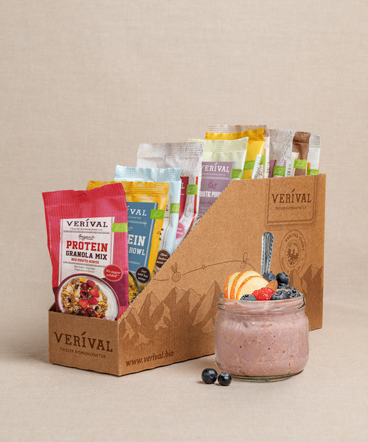 Die Protein-Probierbox Top 10 von Verival Bio enthält 10 verschiedene Einzelportionspackungen von proteinreichen Verival Frühstücksprodukten,  inklusive Granols und Müslia. Davor präsentiert ein Glas Haferflocken mit Früchten ein proteinreiches Frühstück, das perfekt zur Unterstützung deiner Fitnessziele geeignet ist.
