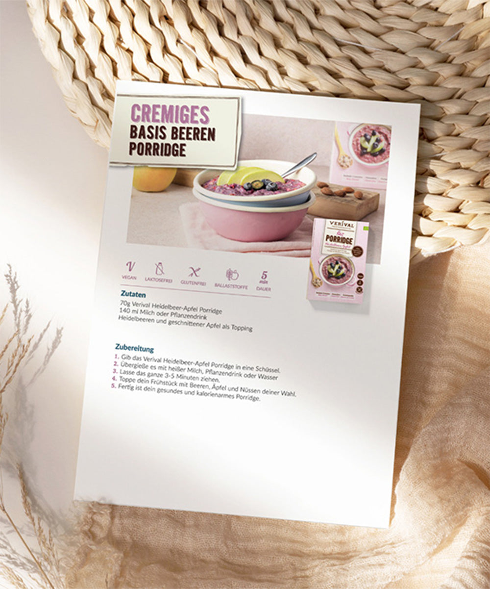 Eine Rezeptkarte auf einer strukturierten Matte zeigt eine Schüssel mit cremigem Beerenporridge. Deutscher Text mit Einzelheiten zu Zutaten und Zubereitungschritten sowie einem Bild eines Produktes der Verival Bio GmbH. Weitere Informationen finden Sie im kostenlosen Ernährungs- und Rezeptguide E-Book in deutscher oder englischer Sprache.