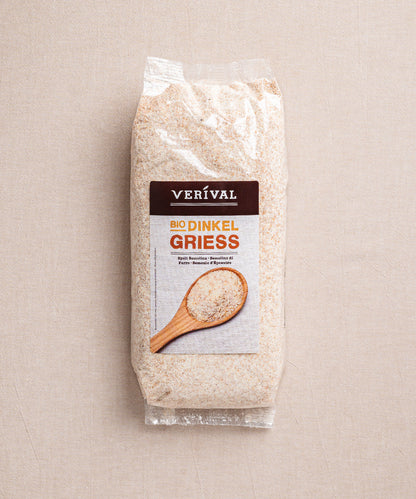 Eine Packung Dinkelgrieß der Verival Bio GmbH zeigt ein Etikett mit einem Holzlöffel voll Grieß. Die transparente Verpackung offenbart die körnige Textur des Grieß, der reich an Ballaststoffen und Proteinen ist.