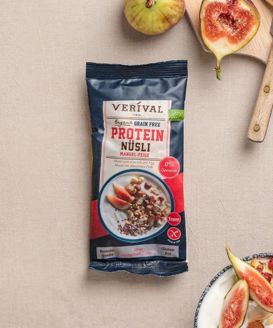Eine Packung Erdbeer-Chia Porridge der Verival Bio GmbH liegt auf einer beigen Fläche, umgeben von frischen Erdbeeren und einer Schüssel Porridge und ist somit ideal für ein vollwertiges Frühstück.