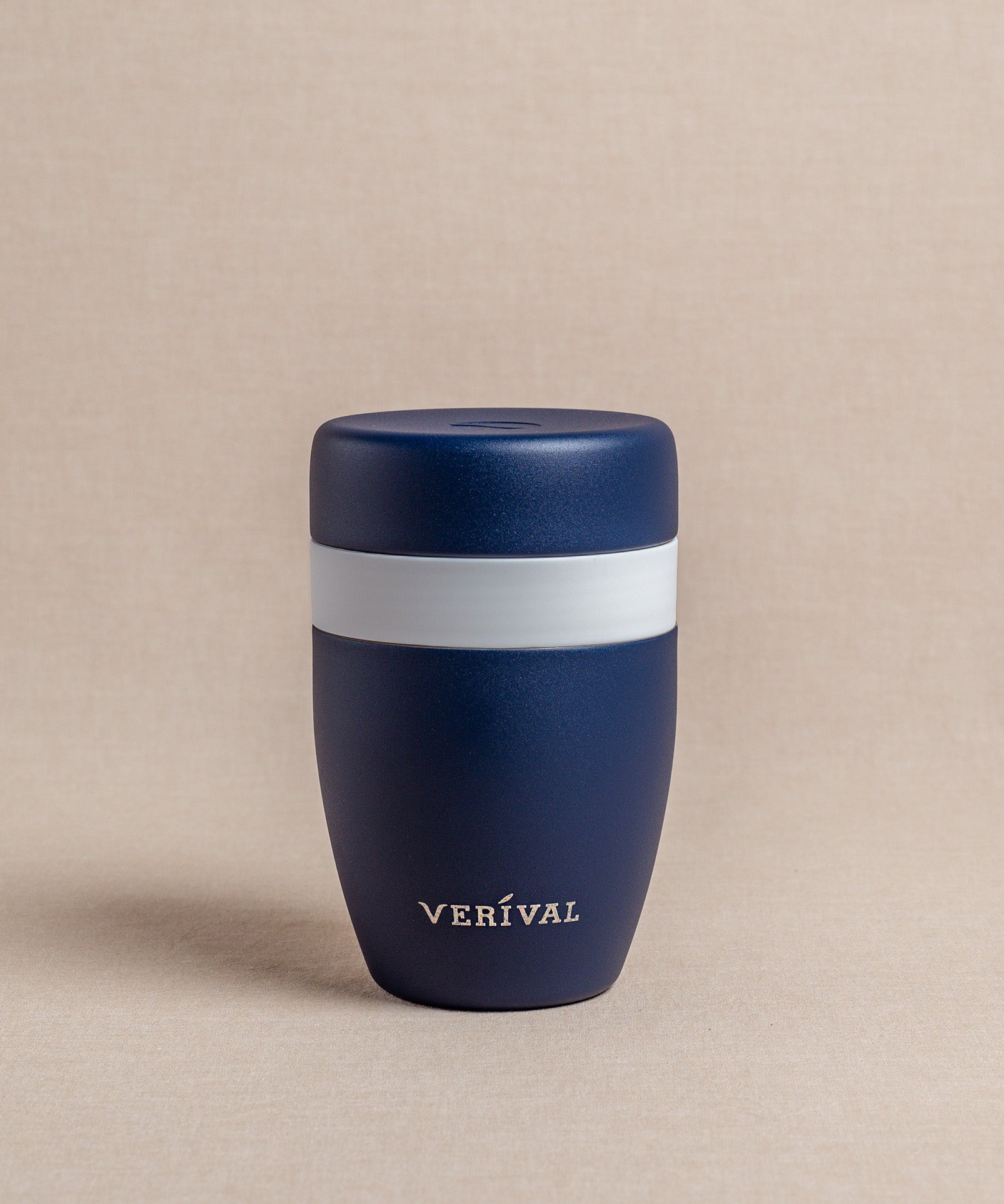 Ein dunkelblauer FLSK Thermosbecher To Go mit einem auffälligen weißen Band um die Mitte, elegant platziert auf einem neutralen Hintergrund.